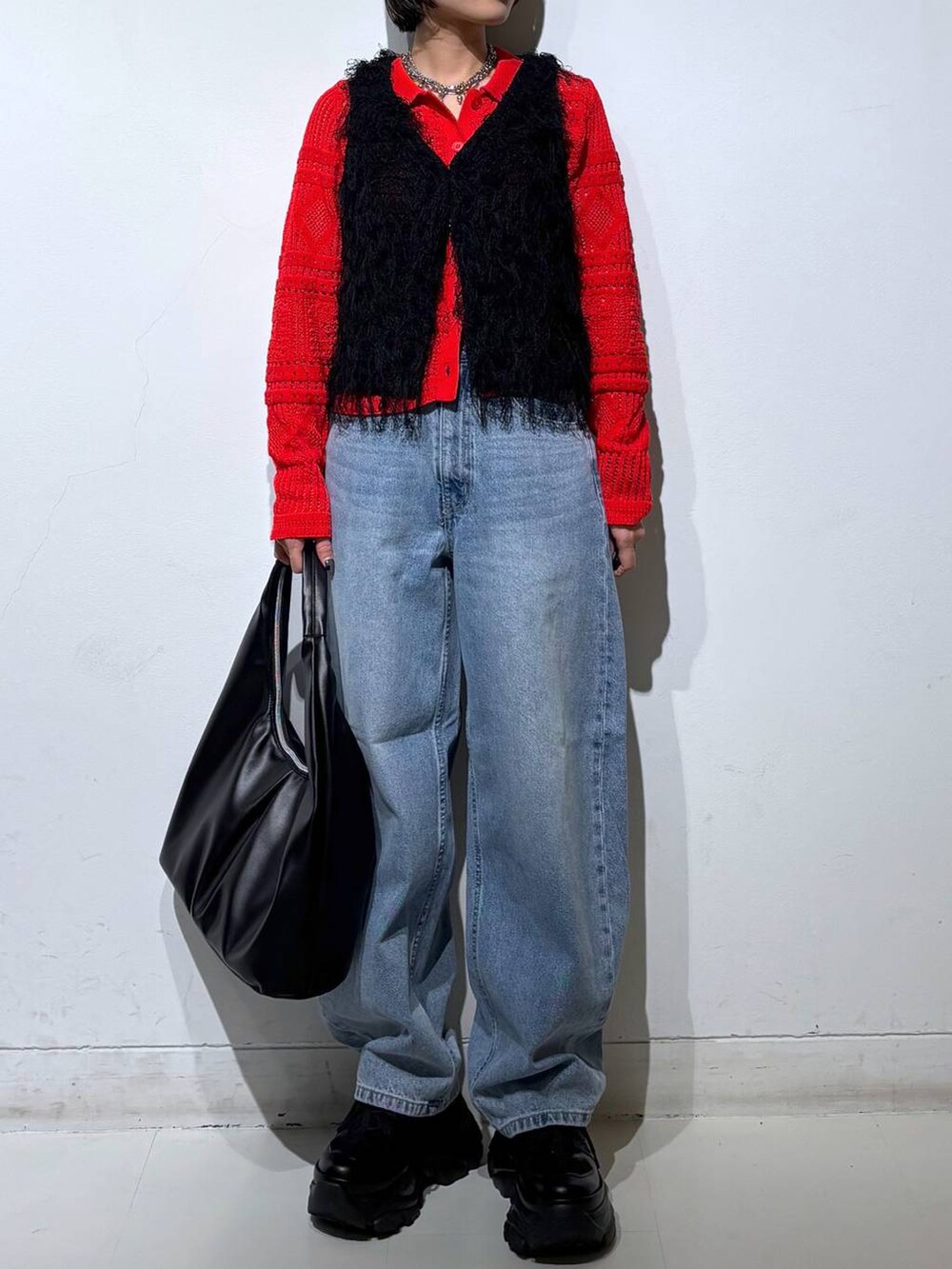 ブラック系のスニーカー、ブルー系のデニムパンツ、ブラック系のベストを着用したレディースの春コーディネートの3枚目の写真