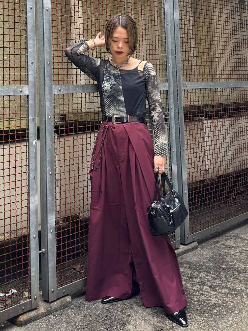 ブラック系のショルダーバッグ、レッド系のスラックス、ブラック系のサンダルを着用したレディースの夏コーディネートの4枚目の写真