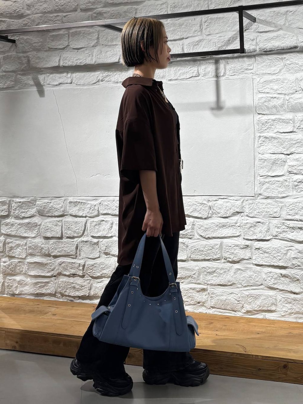 ブラック系のスニーカー、ブラック系のデニムパンツ、ブルー系のハンドバッグを着用したレディースの春コーディネートの4枚目の写真