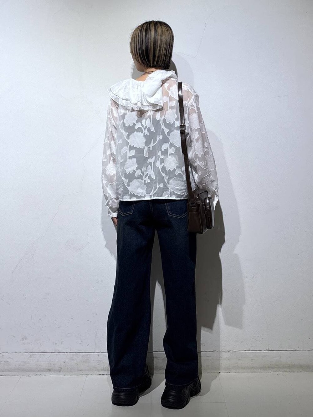 ブラック系のスニーカー、ブラック系のキャミソール、ブルー系のスラックスを着用したレディースの春コーディネートの5枚目の写真