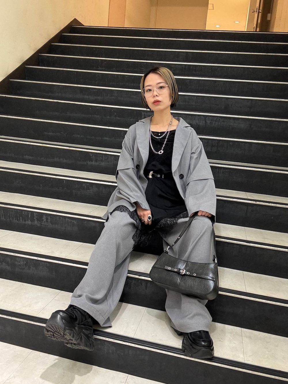 ブラック系のスニーカー、ブラック系のチュニック、ブラック系のハンドバッグを着用したレディースの春コーディネートの9枚目の写真