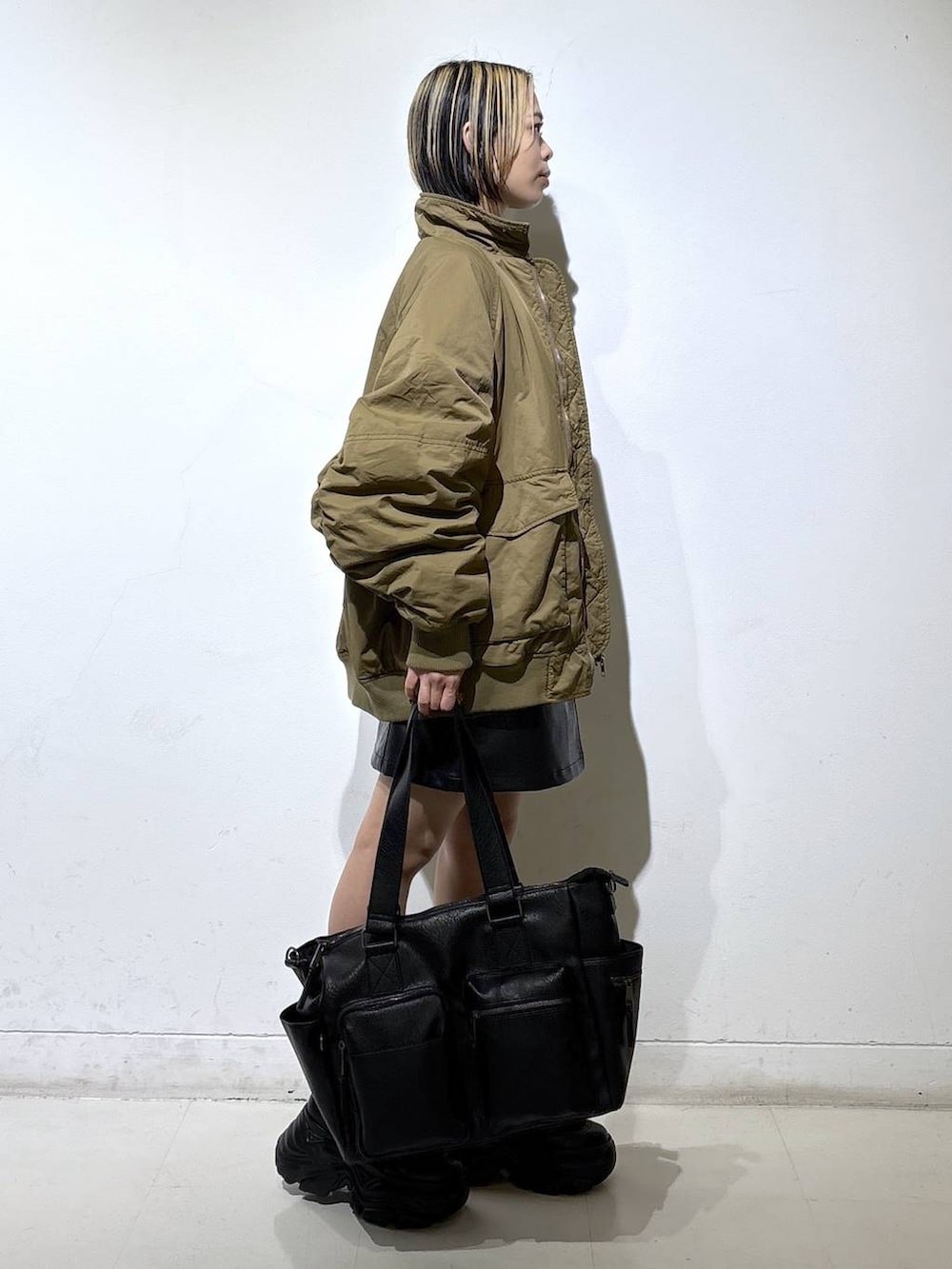 ブラック系のブーツ、ブラック系のボストンバッグ、ブラック系のスカートを着用したレディースの冬コーディネートの3枚目の写真