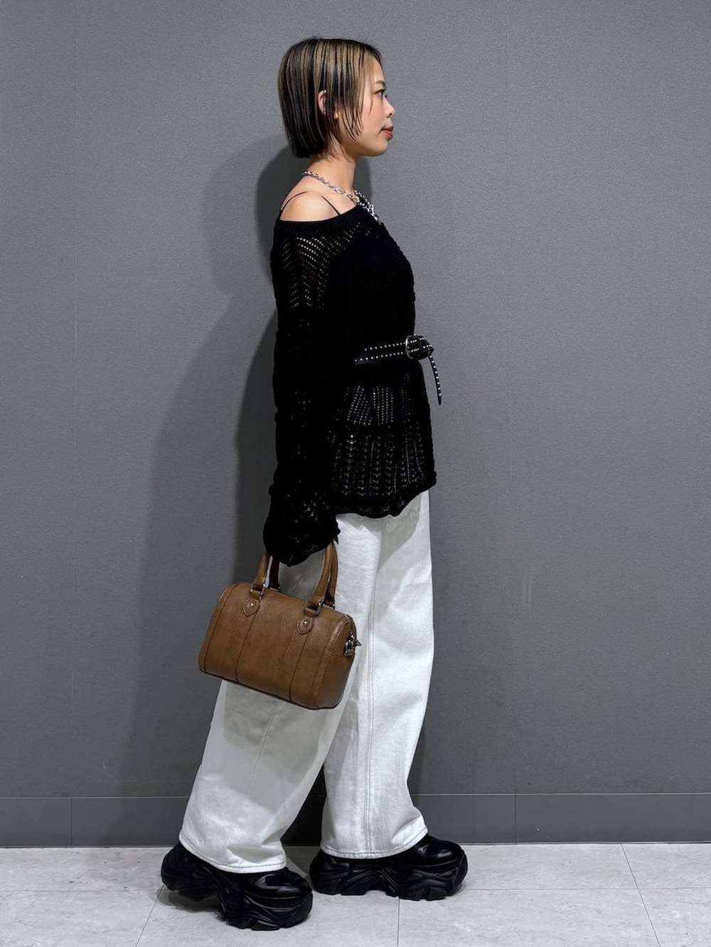 ブラック系のスニーカー、ブラック系のキャミソール、ホワイト系のスラックスを着用したレディースの春コーディネートの4枚目の写真