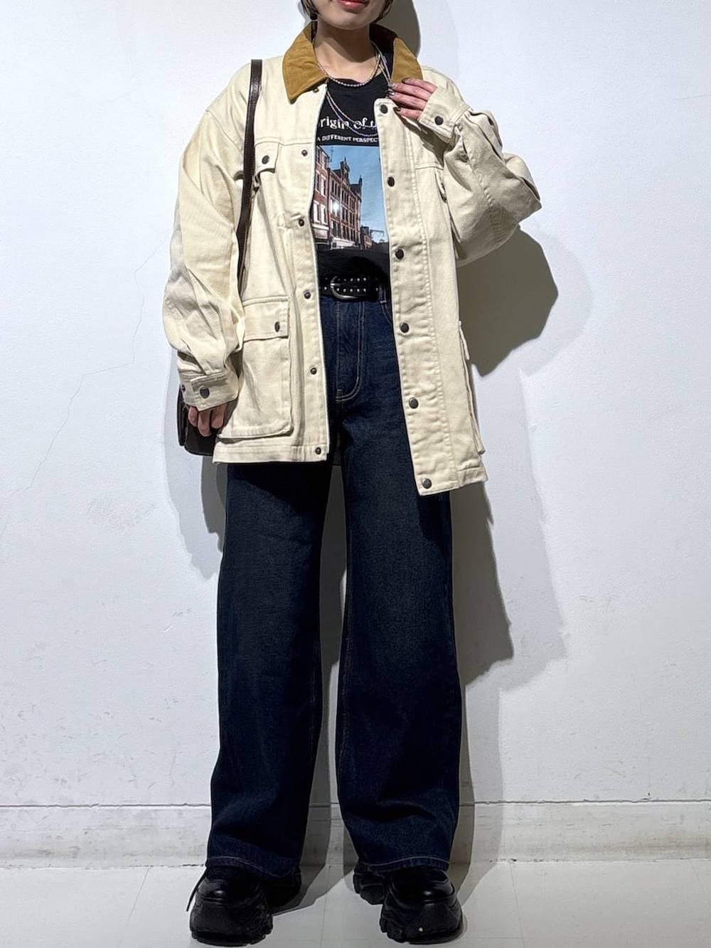 ブラック系のスニーカー、ブルー系のスラックス、ブラウン系のショルダーバッグを着用したレディースの春コーディネートの3枚目の写真