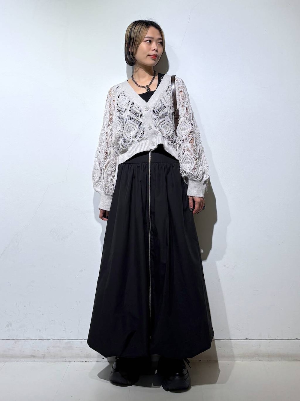 ブラック系のスニーカー、ベージュ系のカーディガン/ボレロ、ブラウン系のショルダーバッグを着用したレディースの春コーディネートの2枚目の写真