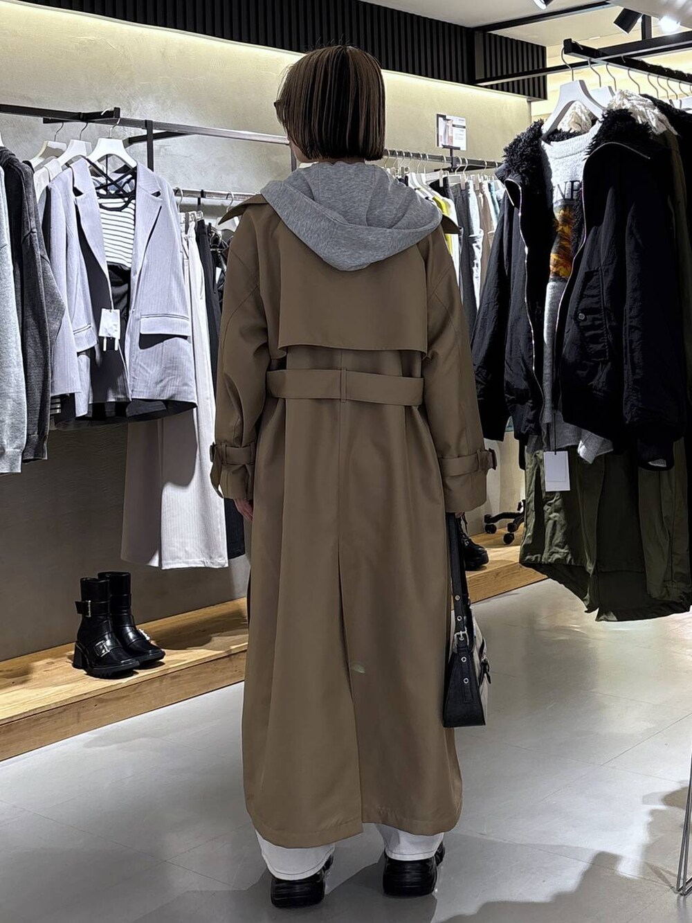 ブラック系のスニーカー、ホワイト系のデニムパンツ、ベージュ系のトレンチコートを着用したレディースの冬コーディネートの4枚目の写真