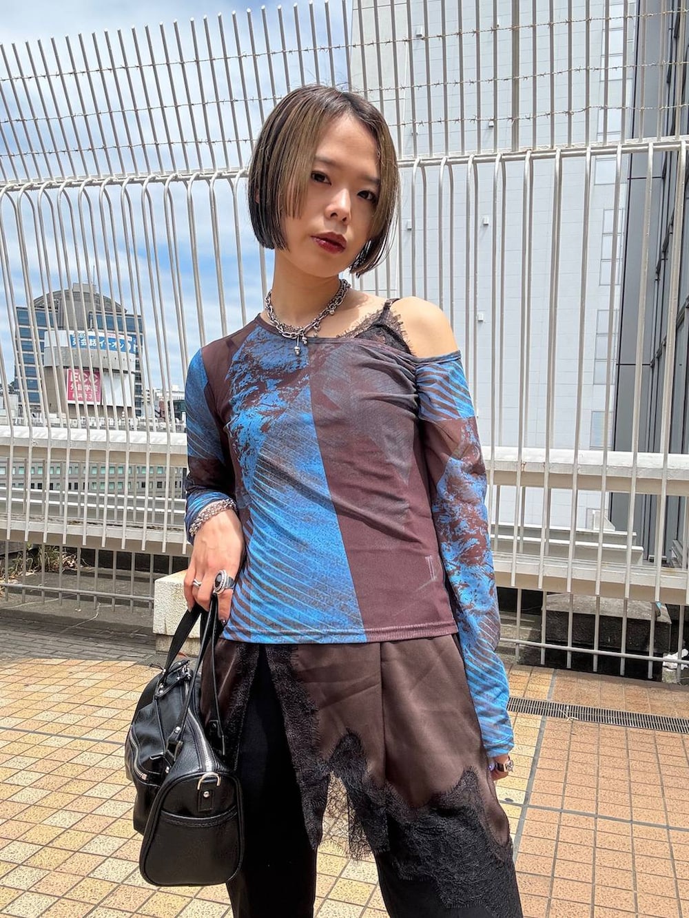 ブラック系のショルダーバッグ、ブラウン系のチュニック、ブラック系のスラックスを着用したレディースの夏コーディネートの7枚目の写真