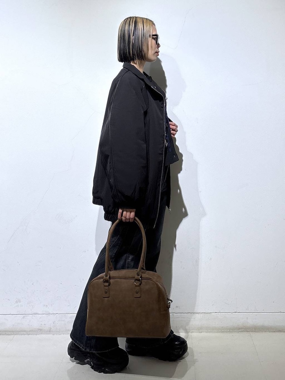 ブラック系のブーツ、ベージュ系のボストンバッグ、ブルー系のデニムパンツを着用したレディースの春コーディネートの3枚目の写真