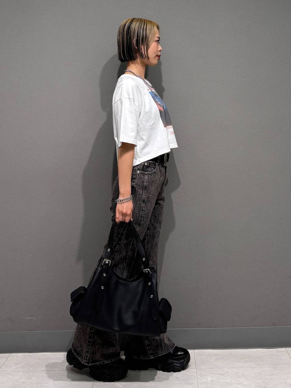 ブラック系のスニーカー、ブラック系のデニムパンツ、ホワイト系のTシャツ/カットソーを着用したレディースの春コーディネートの4枚目の写真