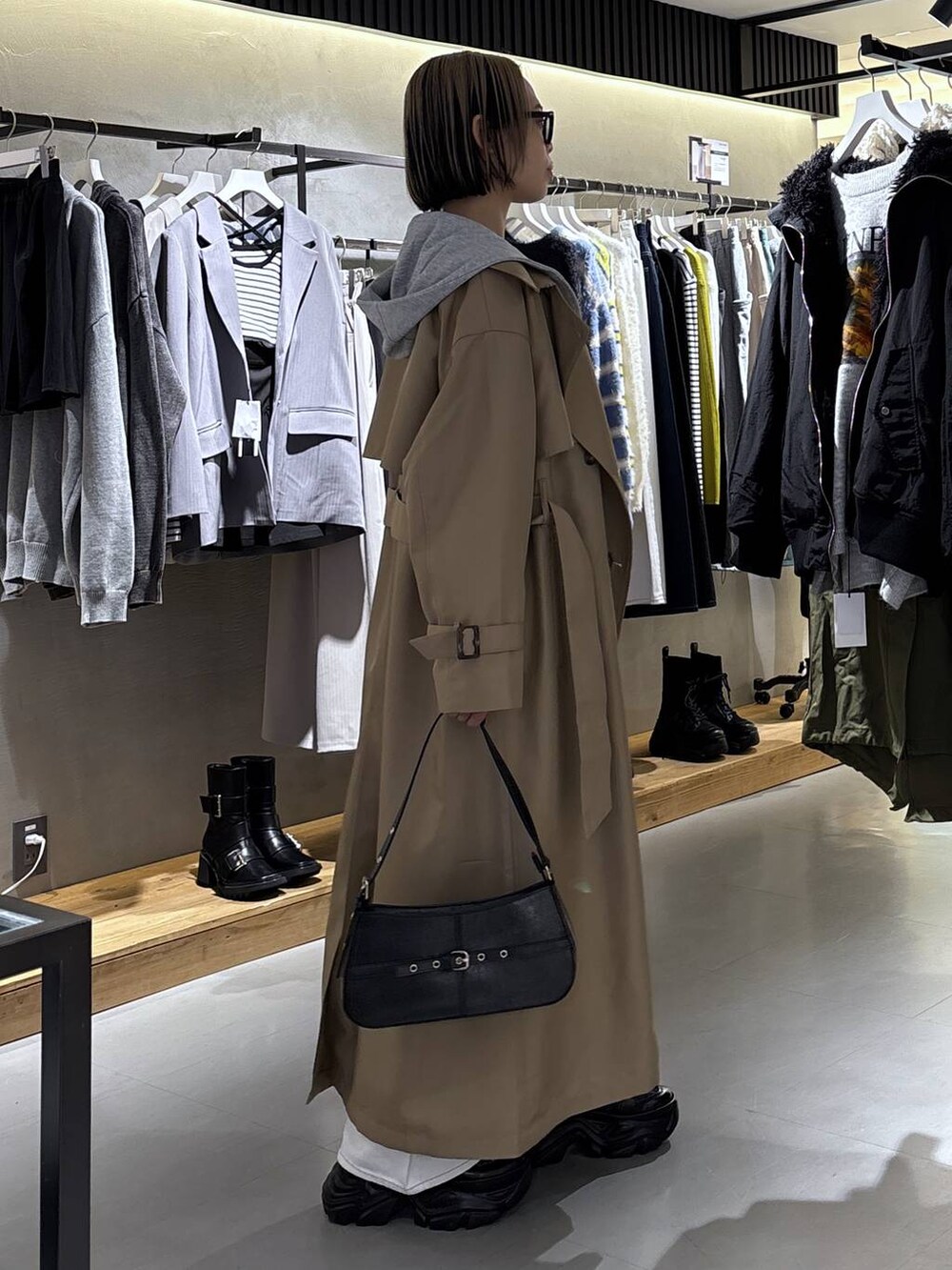 ブラック系のスニーカー、ホワイト系のデニムパンツ、ベージュ系のトレンチコートを着用したレディースの冬コーディネートの3枚目の写真