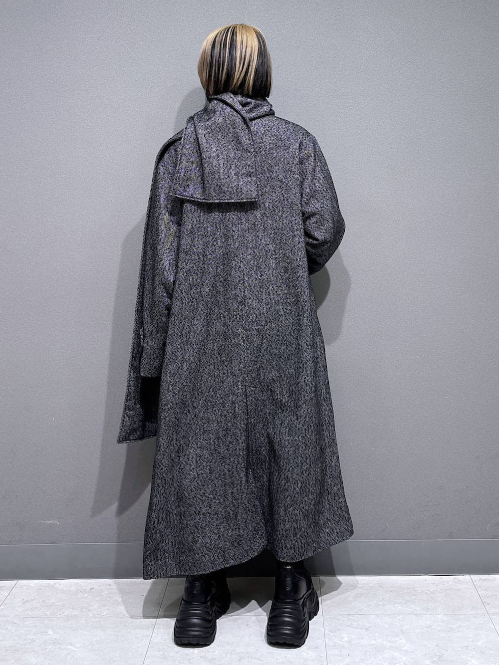 ブラック系のブーツ、ブラック系のチェスターコート、ホワイト系のTシャツ/カットソーを着用したレディースの冬コーディネートの4枚目の写真