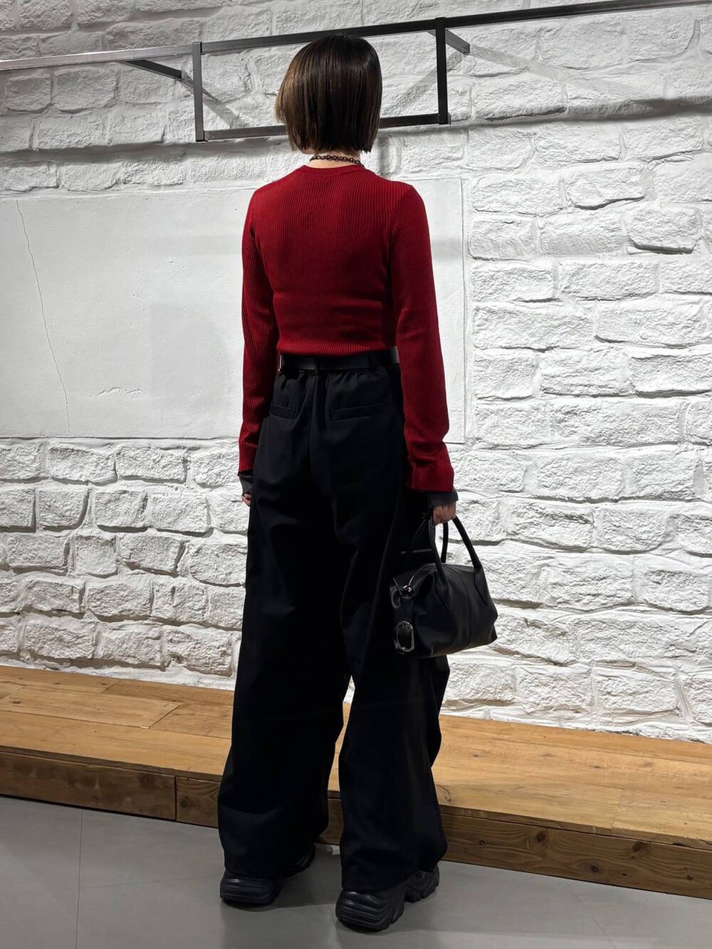 ブラック系のカーゴパンツ、レッド系のニット/セーター、ブラック系のスニーカーを着用したレディースの秋コーディネートの6枚目の写真