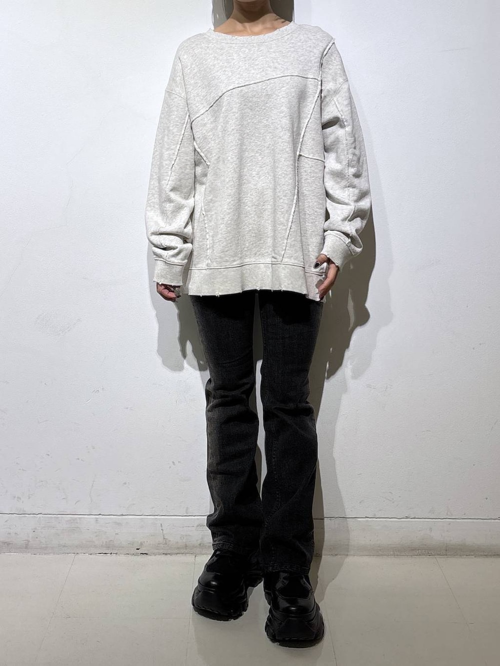 ブラック系のブーツ、ブラック系のデニムパンツ、ベージュ系のスウェットを着用したレディースの秋コーディネートの2枚目の写真