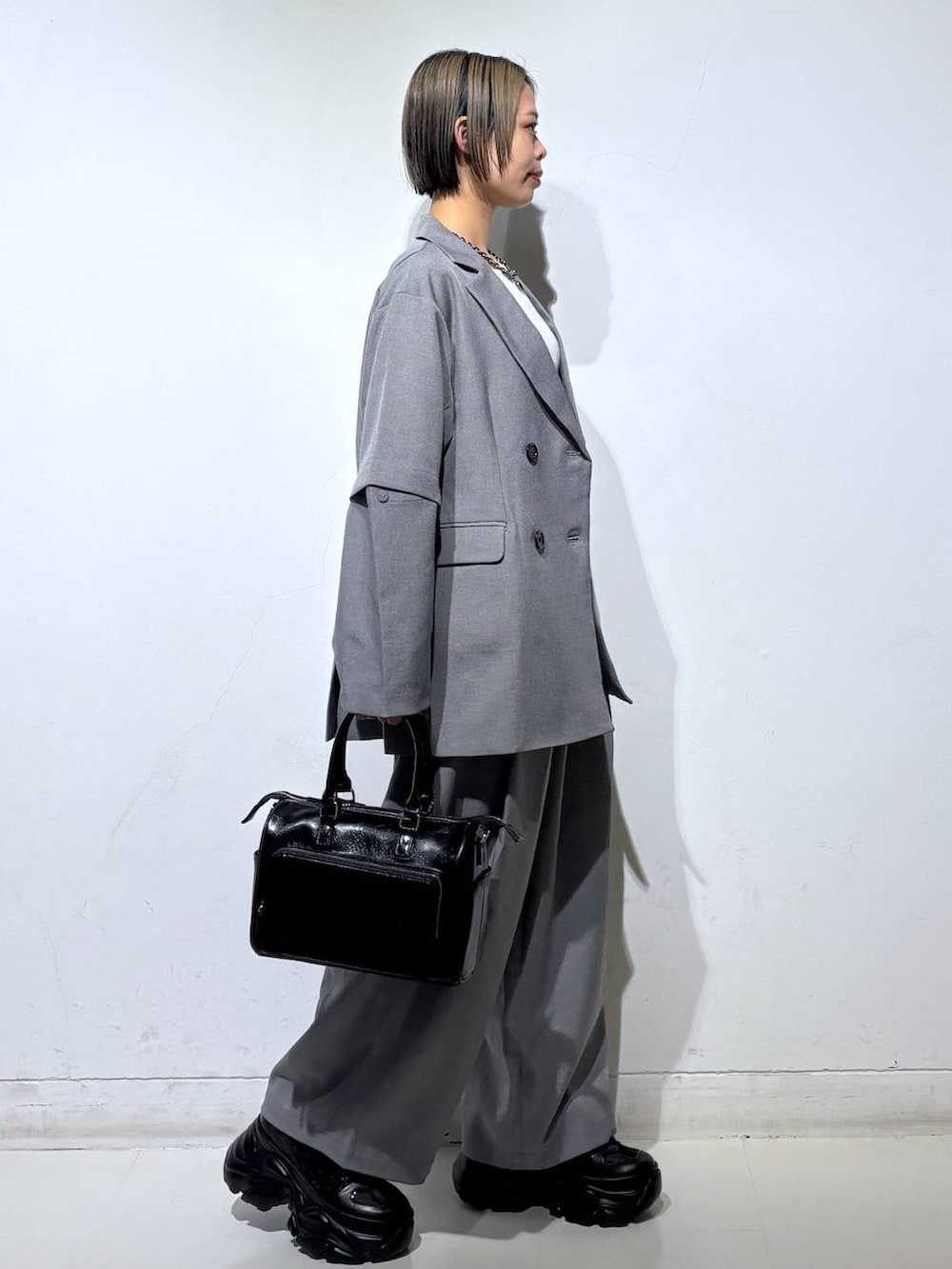 ブラック系のスニーカー、ブラック系のショルダーバッグ、ホワイト系のTシャツ/カットソーを着用したレディースの春コーディネートの3枚目の写真