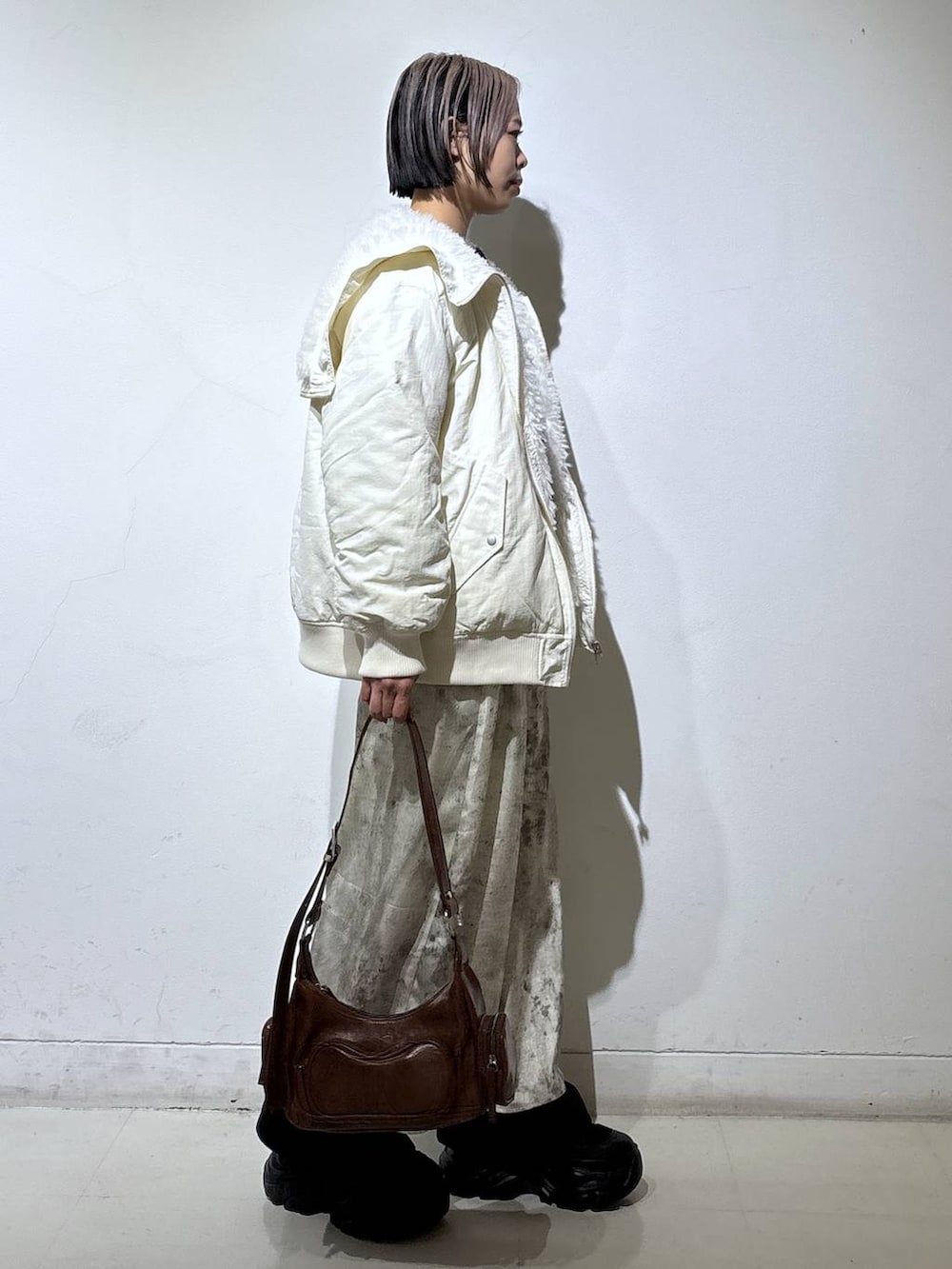 ブラック系のブーツ、ホワイト系のブルゾン、ブラウン系のショルダーバッグを着用したレディースの冬コーディネートの3枚目の写真