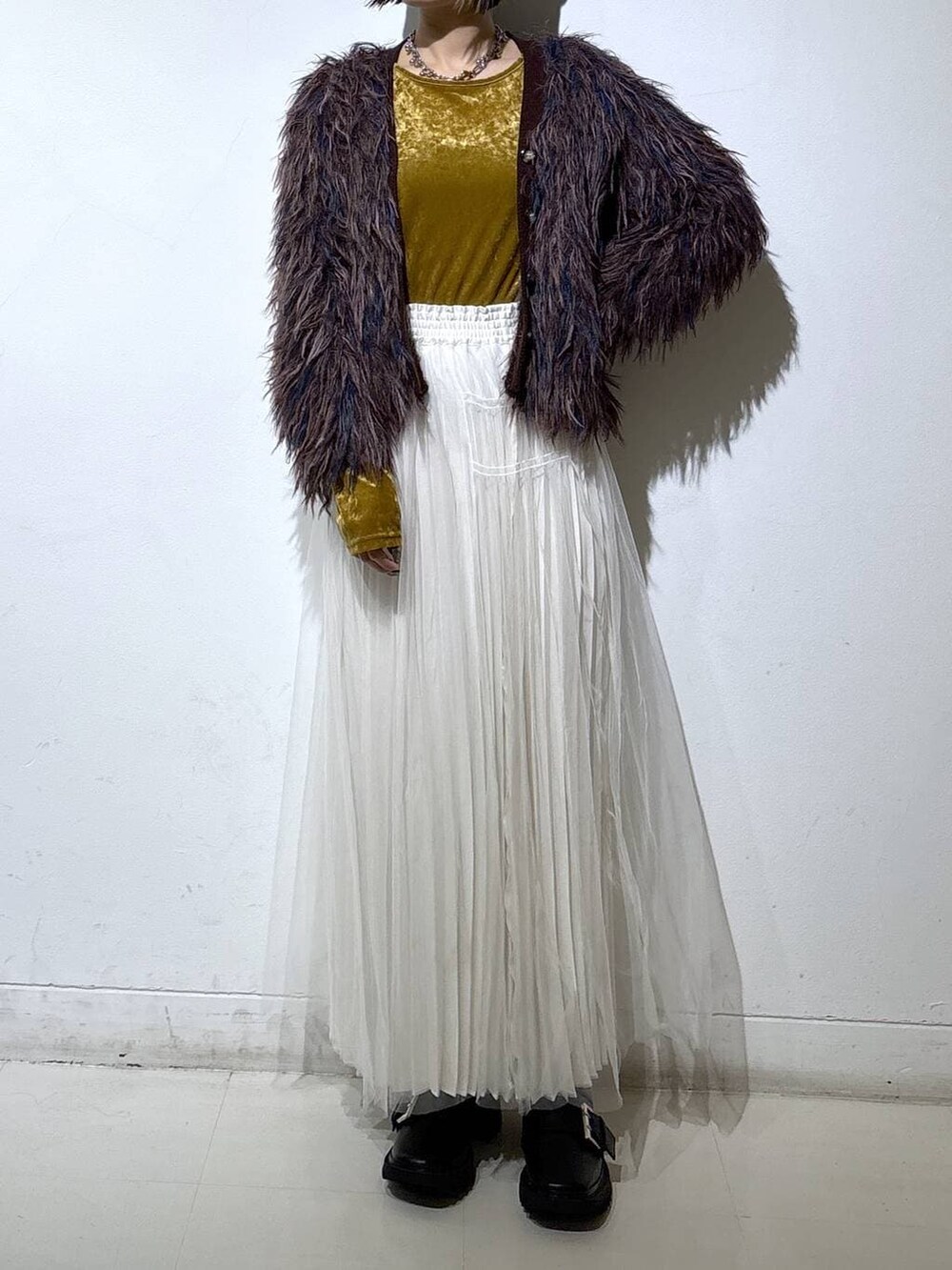 ブラック系のブーツ、ホワイト系のスカート、ブラウン系のカーディガン/ボレロを着用したレディースの冬コーディネートの2枚目の写真