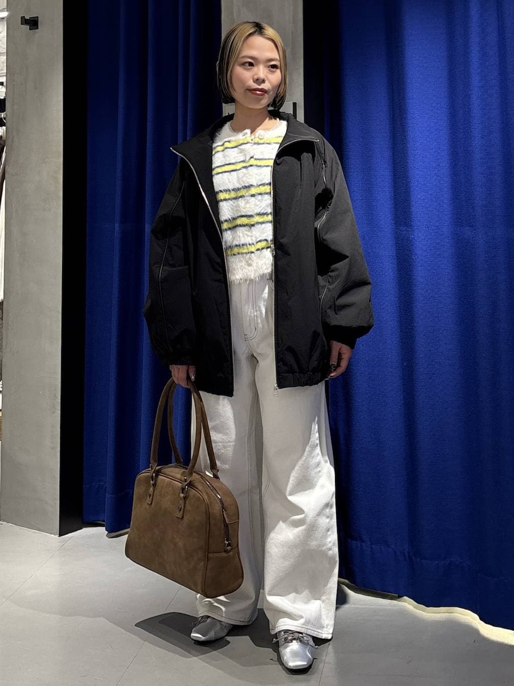 ベージュ系のボストンバッグ、ホワイト系のスラックス、ブラック系のナイロンジャケットを着用したレディースの冬コーディネートの3枚目の写真