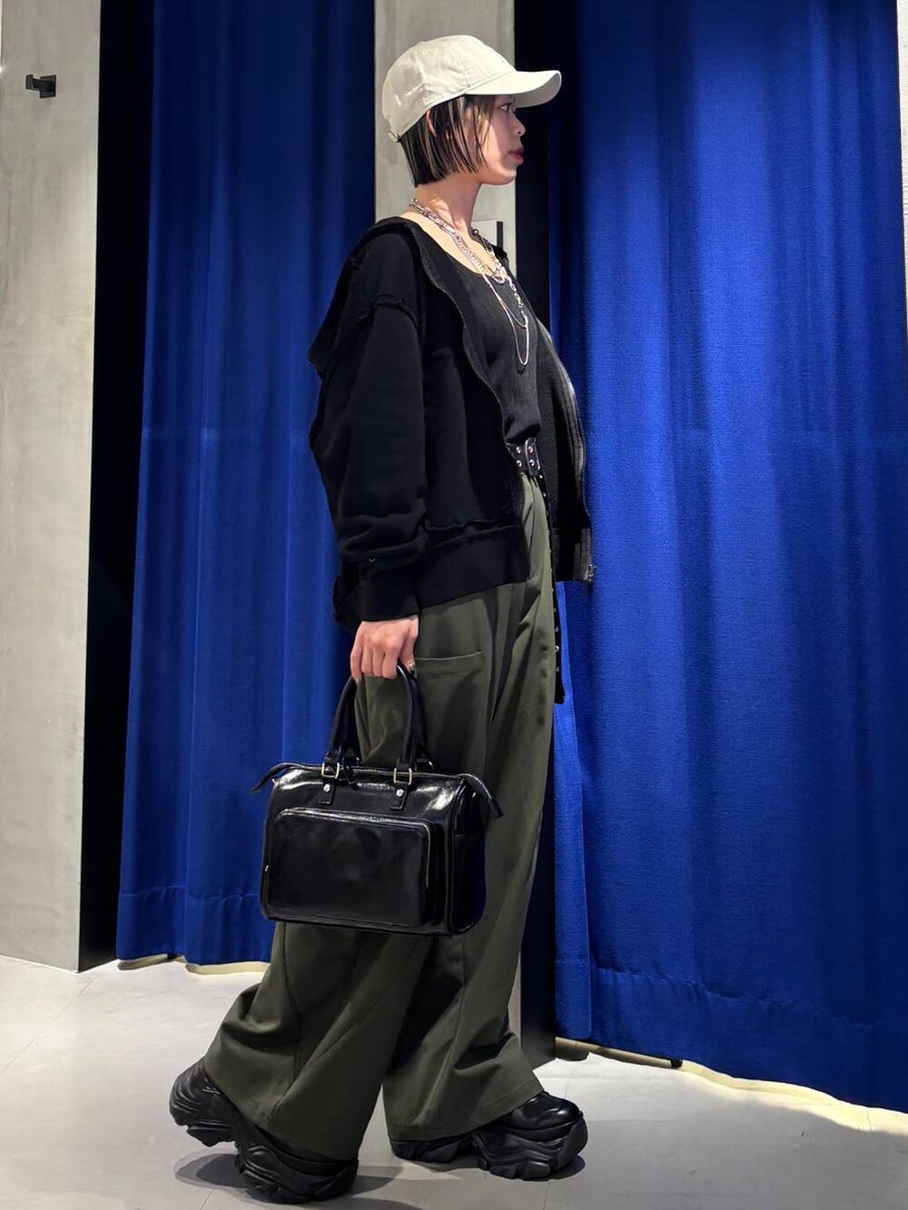 ブラック系のショルダーバッグ、ブラック系のタンクトップ、グリーン系のカーゴパンツを着用したレディースの春コーディネートの5枚目の写真