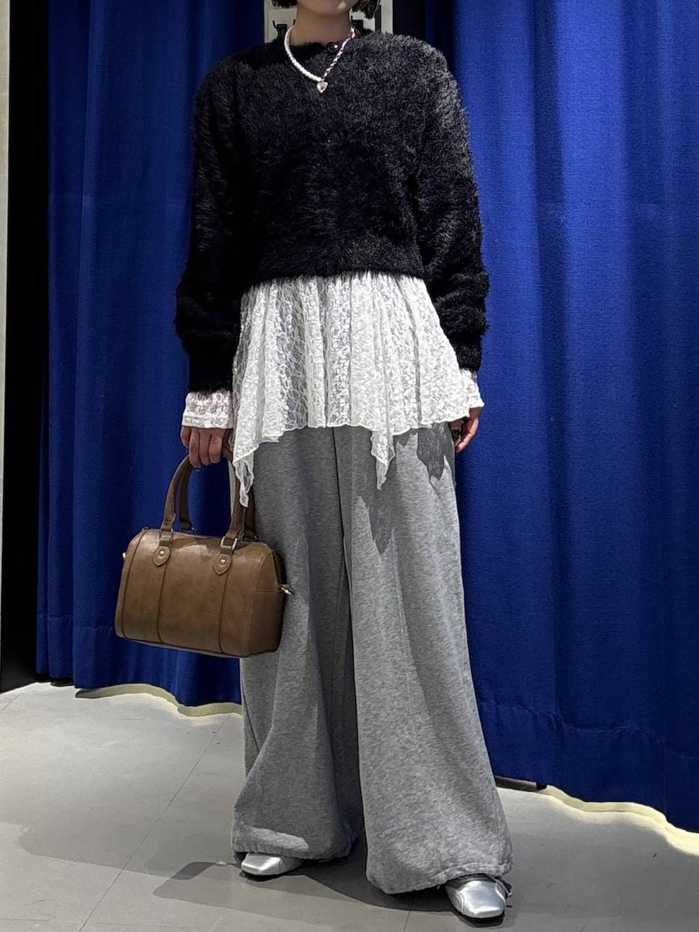 ブラウン系のボストンバッグ、グレー系のスウェットパンツ、シルバー系のスニーカーを着用したレディースの冬コーディネートの2枚目の写真