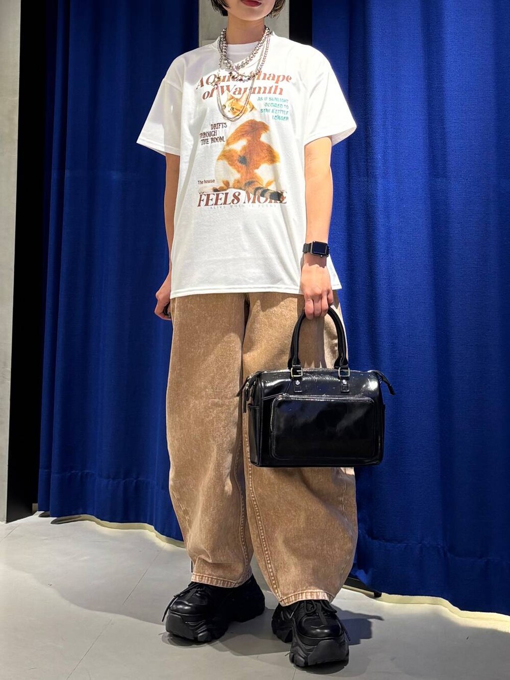 ブラック系のスニーカー、ブラウン系のデニムパンツ、ブラック系のショルダーバッグを着用したレディースの春コーディネートの4枚目の写真