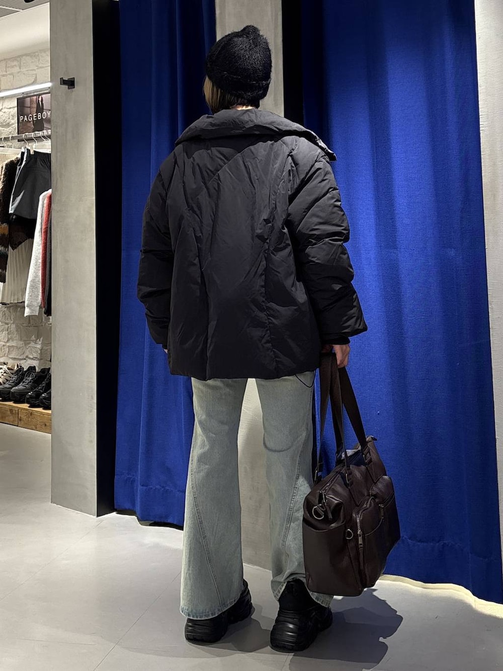 ブラック系のスニーカー、ブルー系のデニムパンツ、ブラウン系のボストンバッグを着用したレディースの冬コーディネートの4枚目の写真