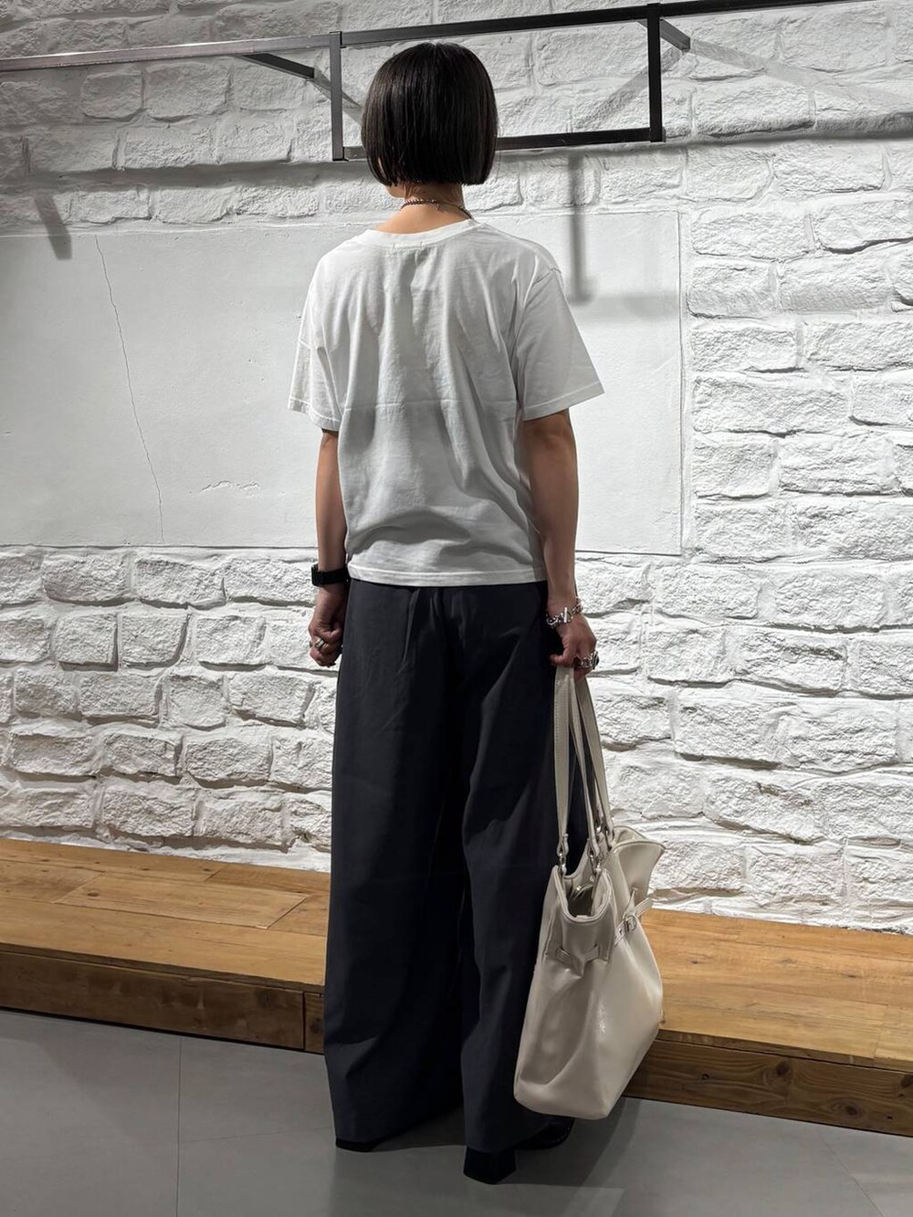 グレー系のスラックス、ホワイト系のTシャツ/カットソー、ホワイト系のショルダーバッグを着用したレディースの夏コーディネートの6枚目の写真