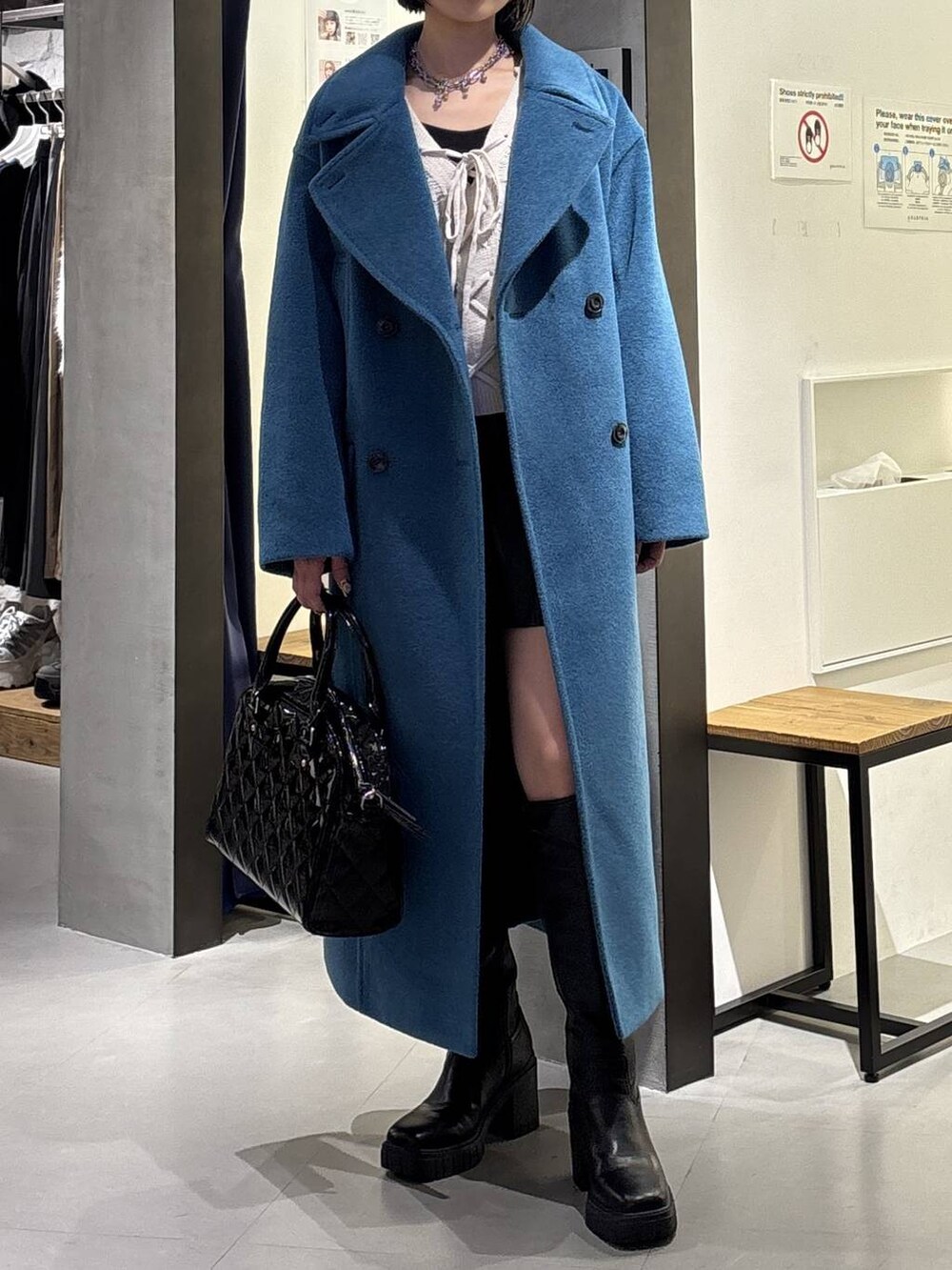 グリーン系のチェスターコート、ブラック系のブーツ、ブラック系のその他パンツを着用したレディースの冬コーディネートの2枚目の写真