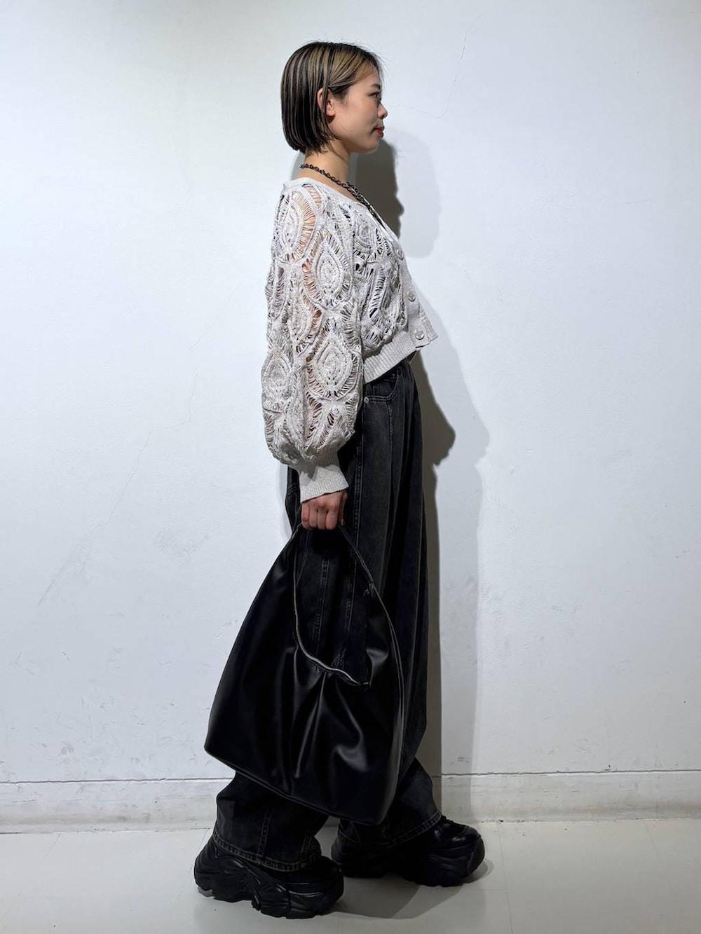 ブラック系のスニーカー、ベージュ系のカーディガン/ボレロ、ブラック系のデニムパンツを着用したレディースの春コーディネートの4枚目の写真