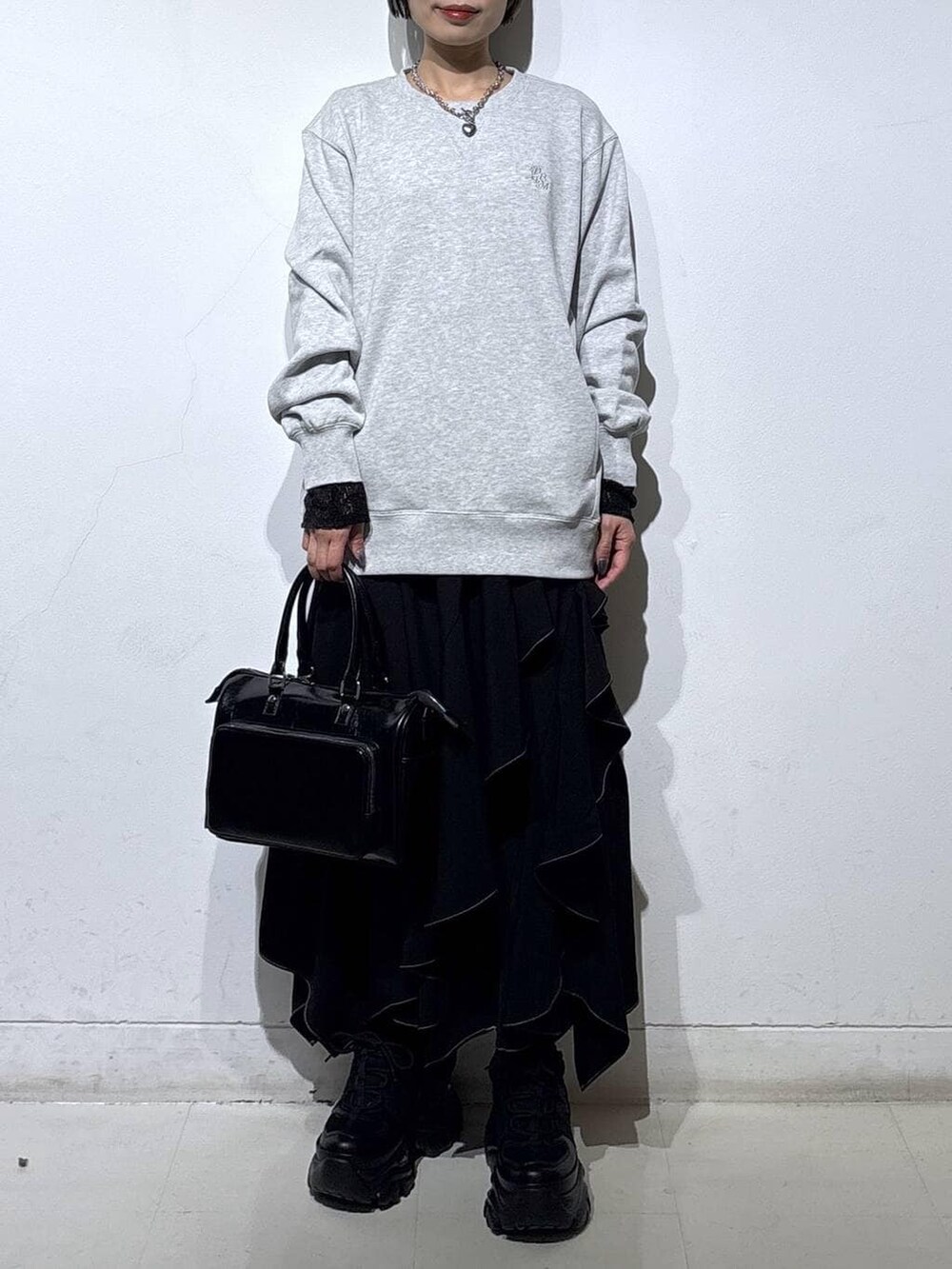 ブラック系のスニーカー、グレー系のスウェット、ブラック系のスカートを着用したレディースの春コーディネートの2枚目の写真