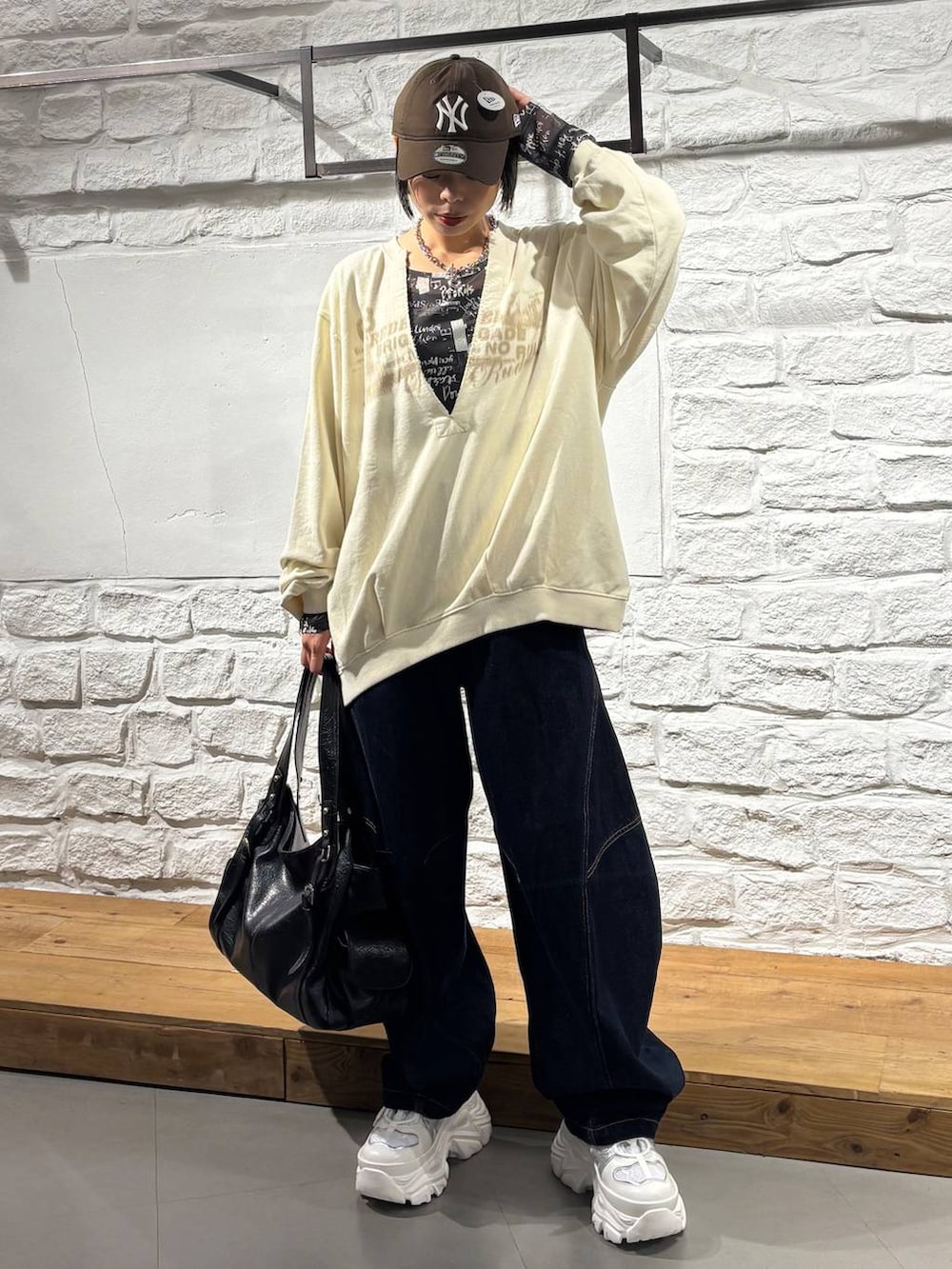 ブルー系のデニムパンツ、ホワイト系のスニーカー、ブラック系のトートバッグを着用したレディースの秋コーディネートの2枚目の写真