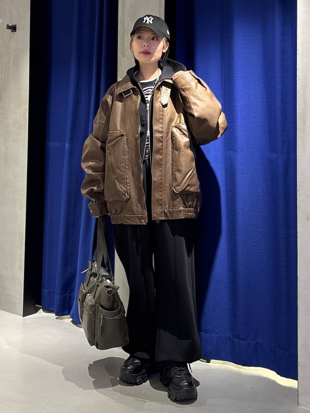 ブラック系のスニーカー、グリーン系のボストンバッグ、ブラック系のTシャツ/カットソーを着用したレディースの冬コーディネートの3枚目の写真