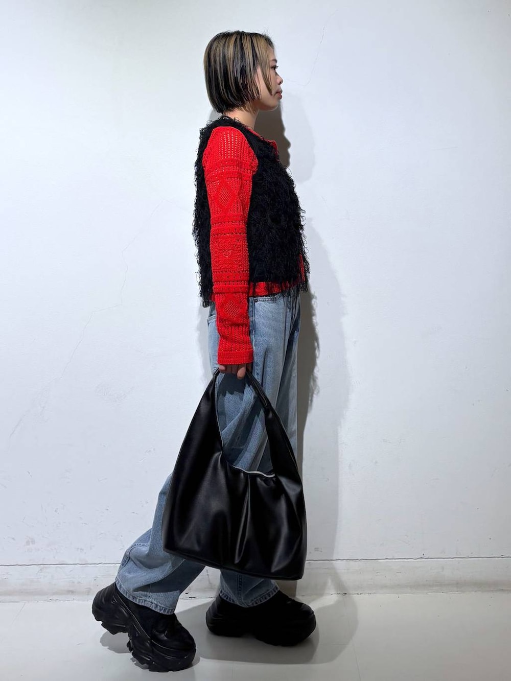 ブラック系のスニーカー、ブルー系のデニムパンツ、ブラック系のベストを着用したレディースの春コーディネートの4枚目の写真