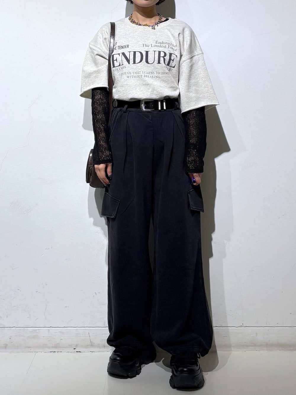 ブラック系のスニーカー、ブラウン系のショルダーバッグ、ブラック系のTシャツ/カットソーを着用したレディースの春コーディネートの3枚目の写真