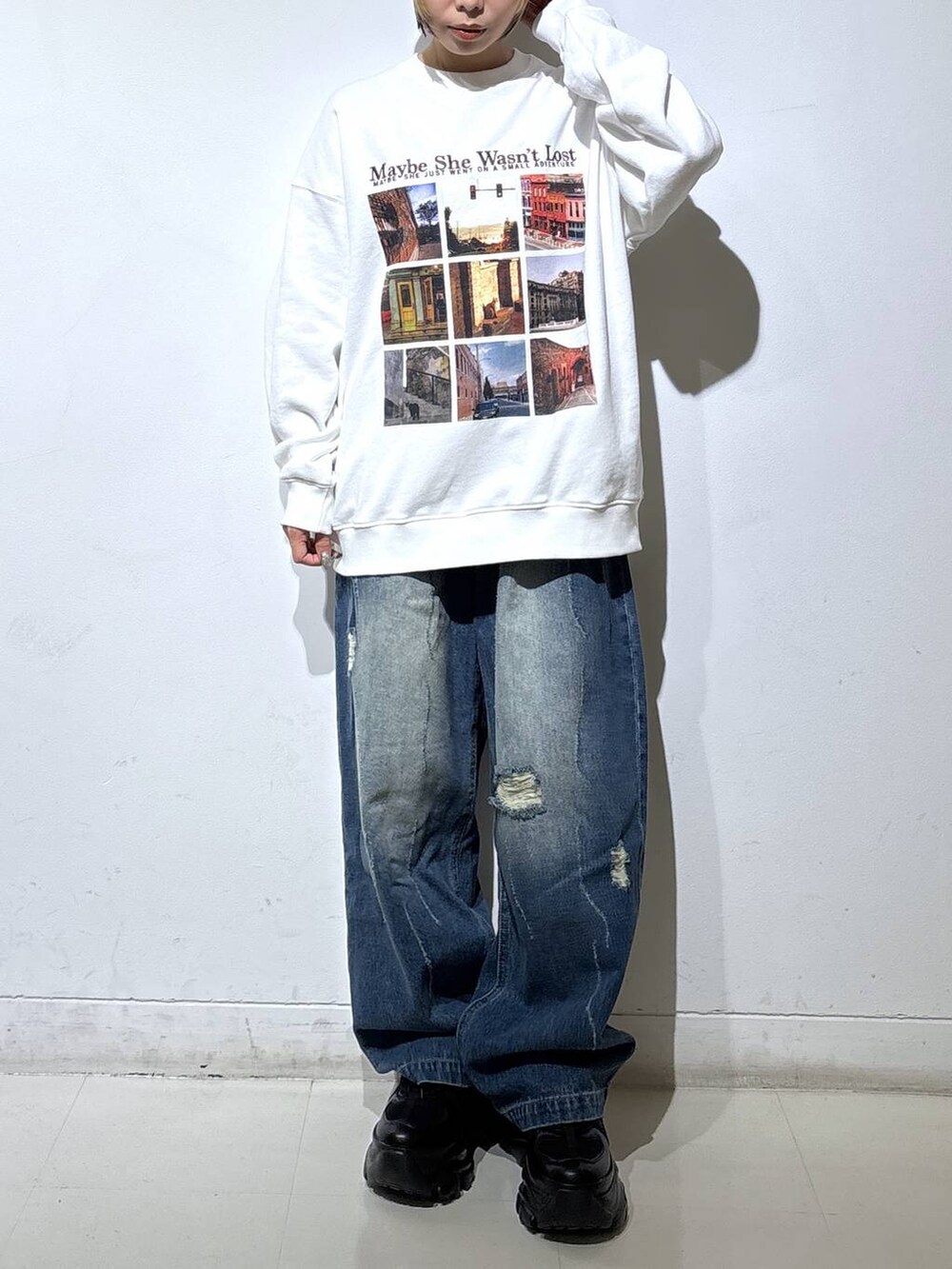 ブラック系のブーツ、ブルー系のデニムパンツ、ホワイト系のスウェットを着用したレディースの秋コーディネートの2枚目の写真