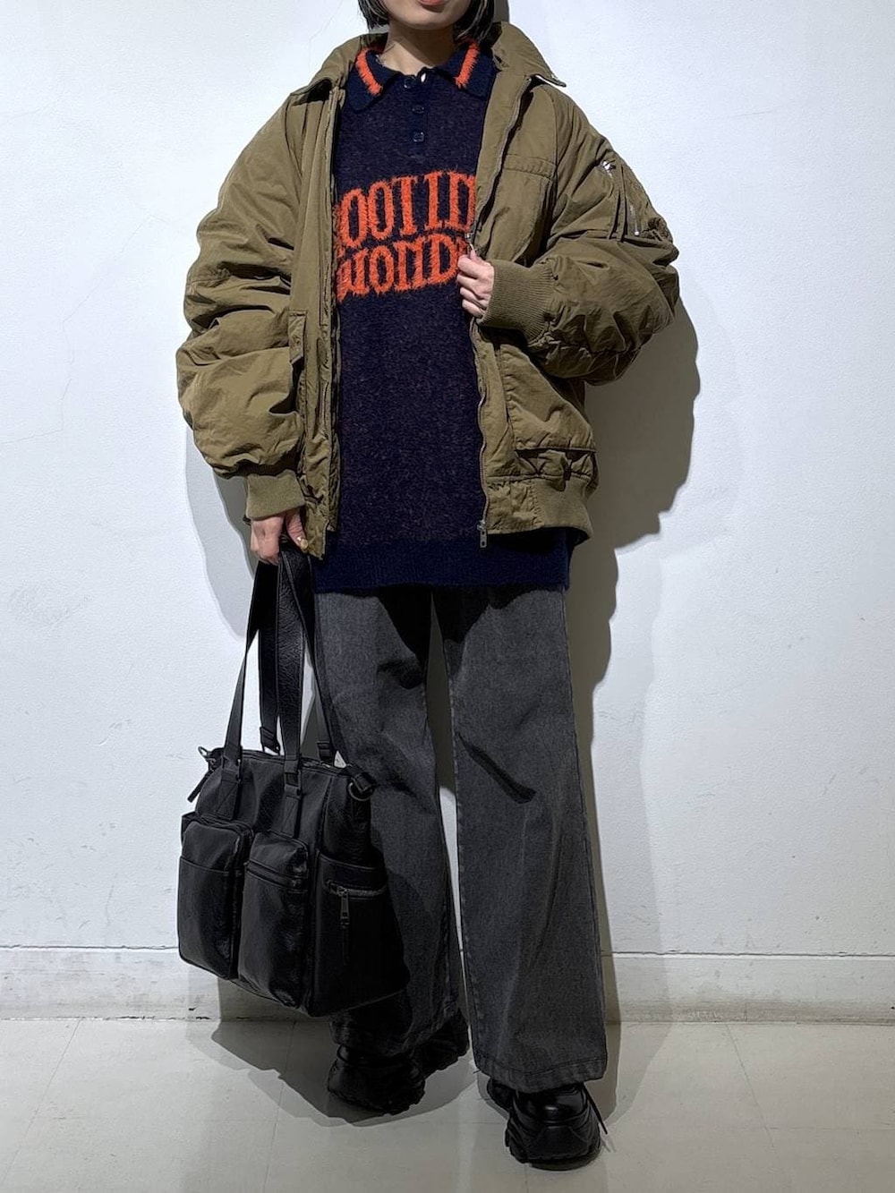 ブラック系のブーツ、ブラック系のボストンバッグ、ブルー系のニット/セーターを着用したレディースの冬コーディネートの2枚目の写真