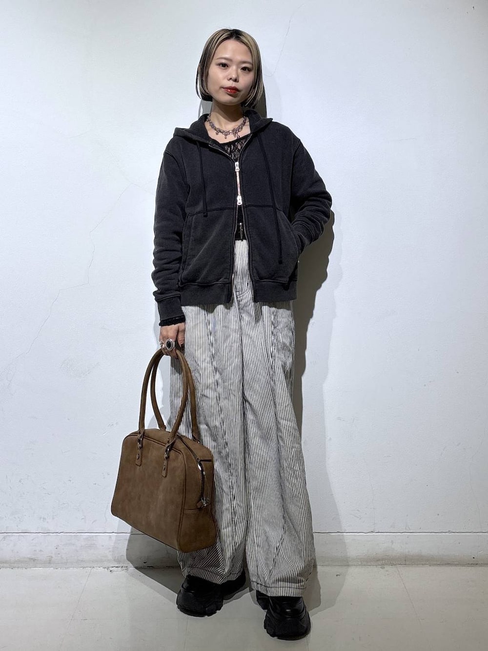 ブラック系のブーツ、ベージュ系のボストンバッグ、ブラック系のTシャツ/カットソーを着用したレディースの冬コーディネートの4枚目の写真