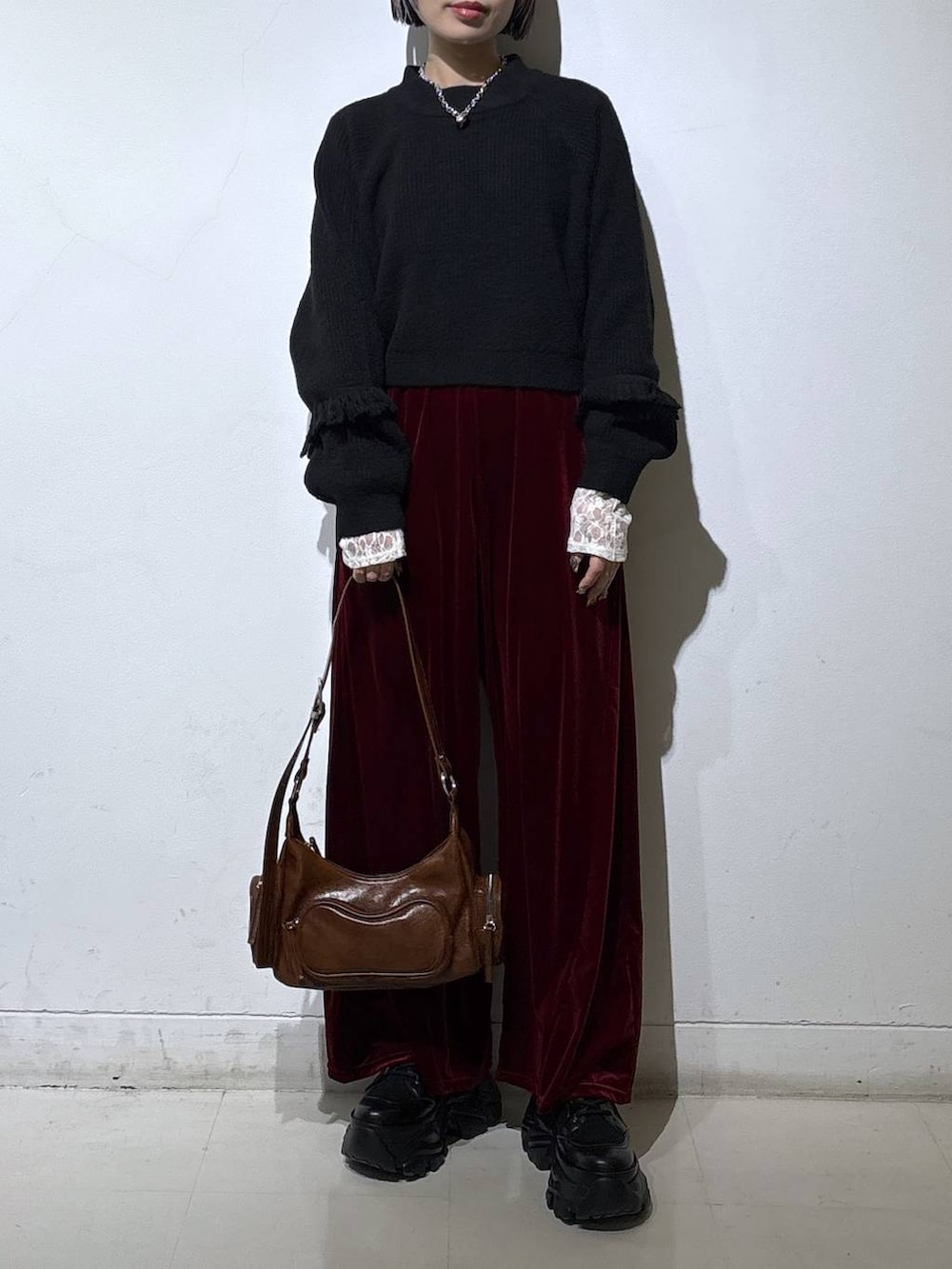 ブラック系のブーツ、ホワイト系のTシャツ/カットソー、ブラウン系のショルダーバッグを着用したレディースの冬コーディネートの2枚目の写真