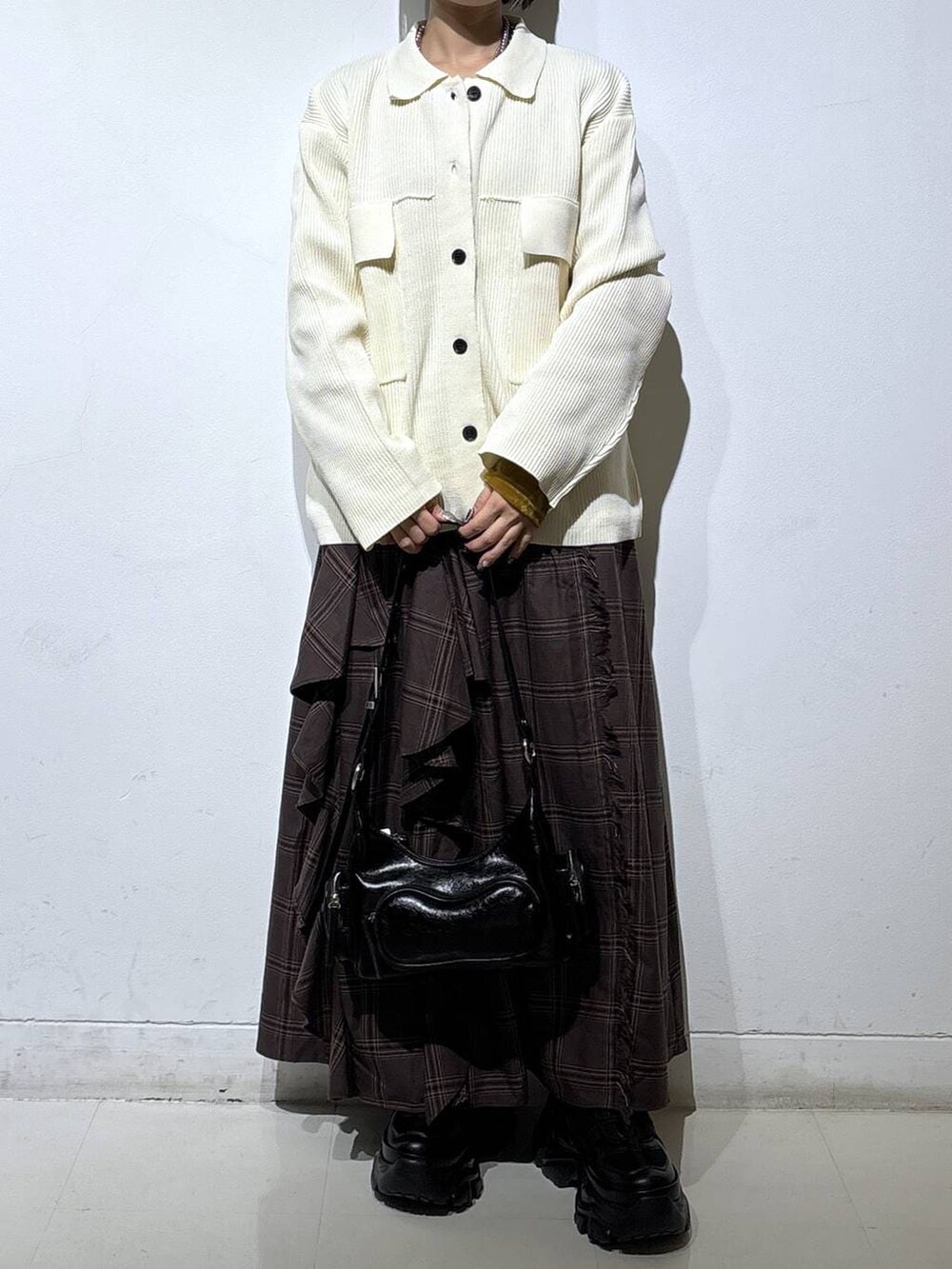 ブラック系のブーツ、ホワイト系のブルゾン、ブラウン系のスカートを着用したレディースの冬コーディネートの2枚目の写真