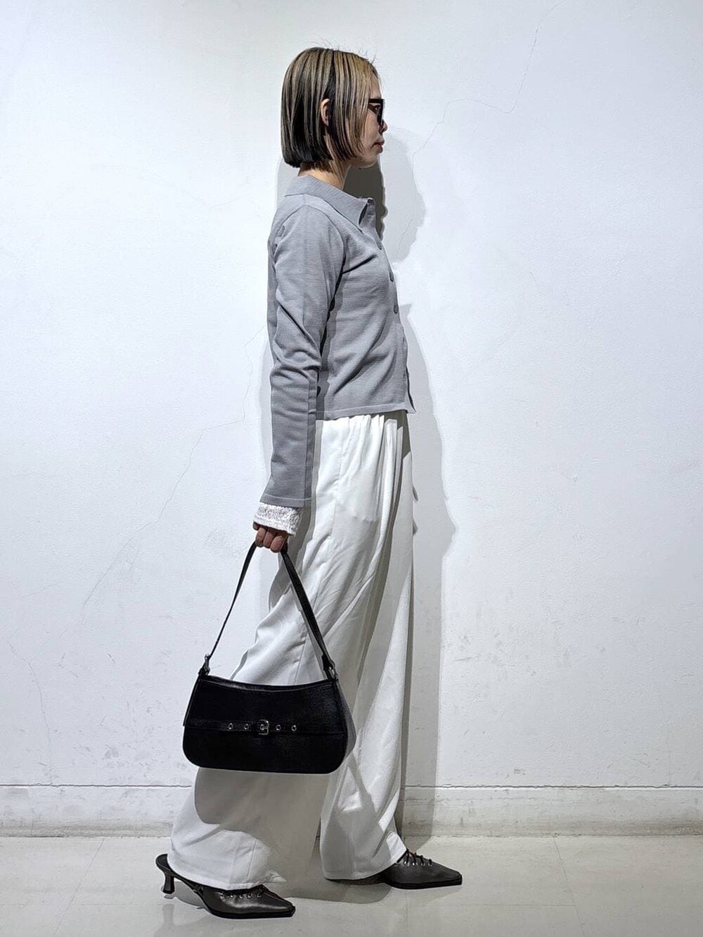 ブラック系のハンドバッグ、ブラウン系のサンダル、ホワイト系のスラックスを着用したレディースの春コーディネートの3枚目の写真