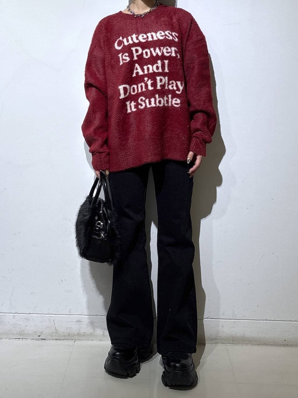 ブラック系のブーツ、ブラック系のデニムパンツ、レッド系のニット/セーターを着用したレディースの冬コーディネートの2枚目の写真