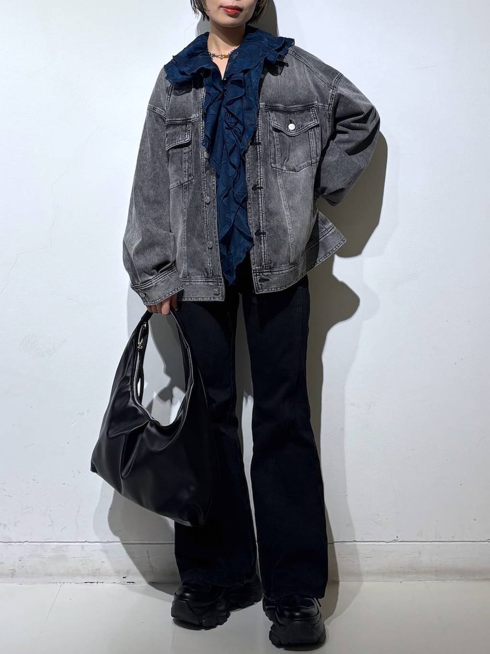 ブラック系のスニーカー、ブラック系のデニムパンツ、ブラック系のブルゾンを着用したレディースの春コーディネートの3枚目の写真