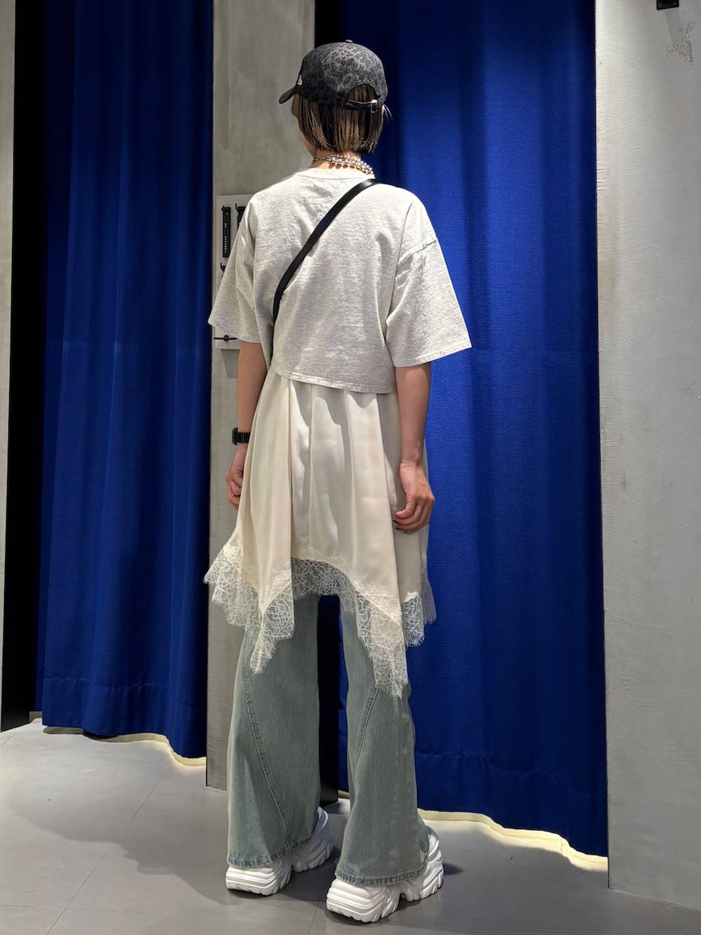 ブラック系のスニーカー、ブルー系のデニムパンツ、ホワイト系のチュニックを着用したレディースの春コーディネートの4枚目の写真