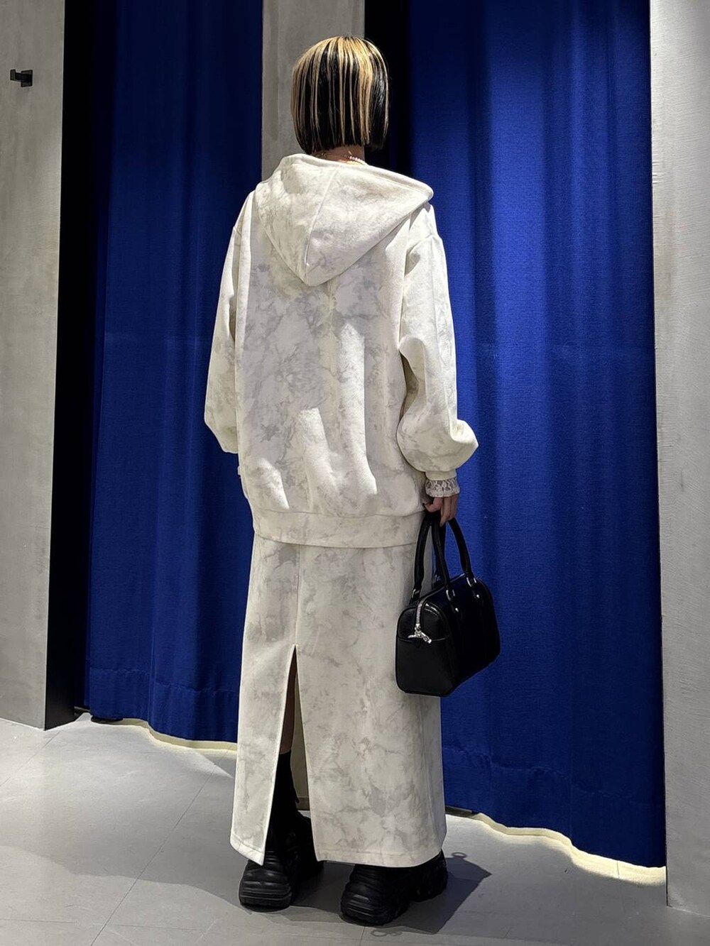 ブラック系のブーツ、ホワイト系のTシャツ/カットソー、ホワイト系のスカートを着用したレディースの冬コーディネートの6枚目の写真