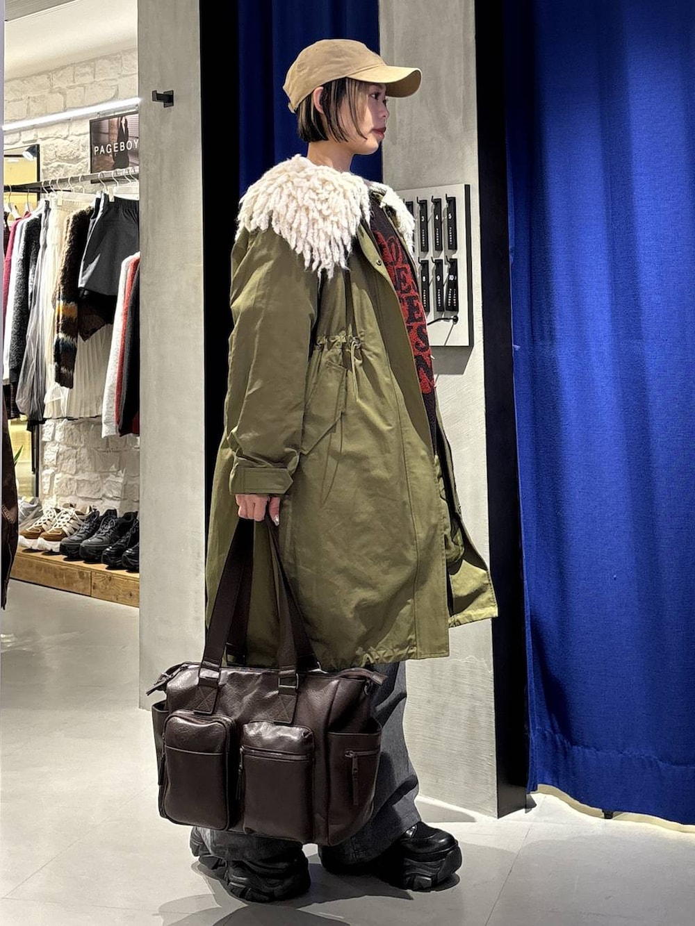 ブラック系のスニーカー、ブラウン系のボストンバッグ、ブラック系のニット/セーターを着用したレディースの冬コーディネートの3枚目の写真