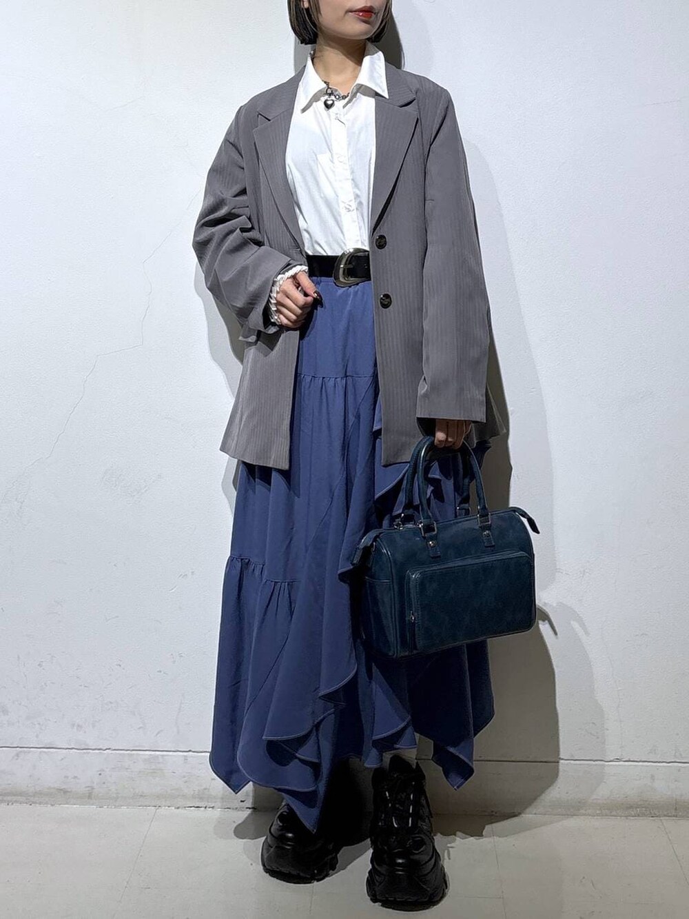 ブラック系のスニーカー、ブルー系のスカート、グレー系のテーラードジャケットを着用したレディースの冬コーディネートの2枚目の写真