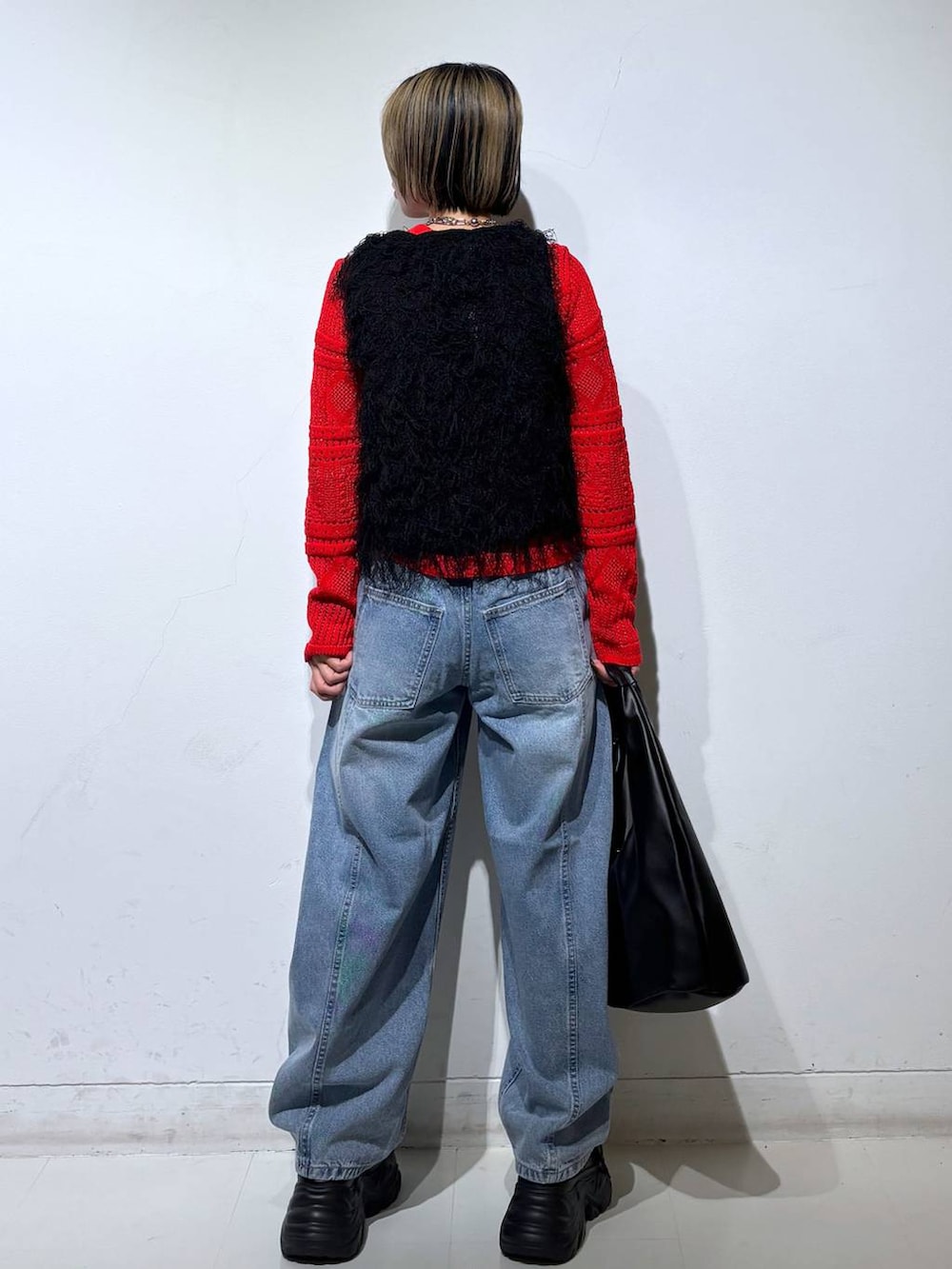 ブラック系のスニーカー、ブルー系のデニムパンツ、ブラック系のベストを着用したレディースの春コーディネートの5枚目の写真