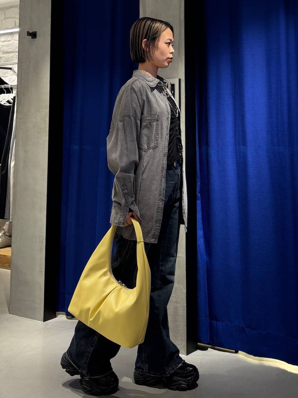 ブラック系のスニーカー、ブルー系のデニムパンツ、ブラック系のシャツ/ブラウスを着用したレディースの春コーディネートの4枚目の写真