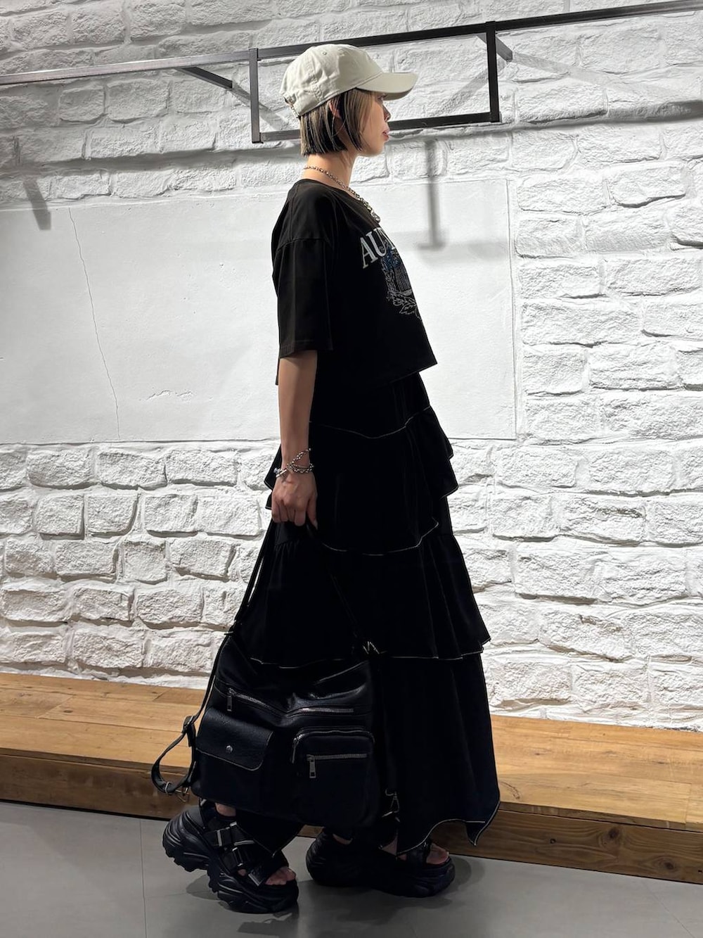ブラック系のスカート、グレー系のTシャツ/カットソー、ブラック系のショルダーバッグを着用したレディースの夏コーディネートの5枚目の写真