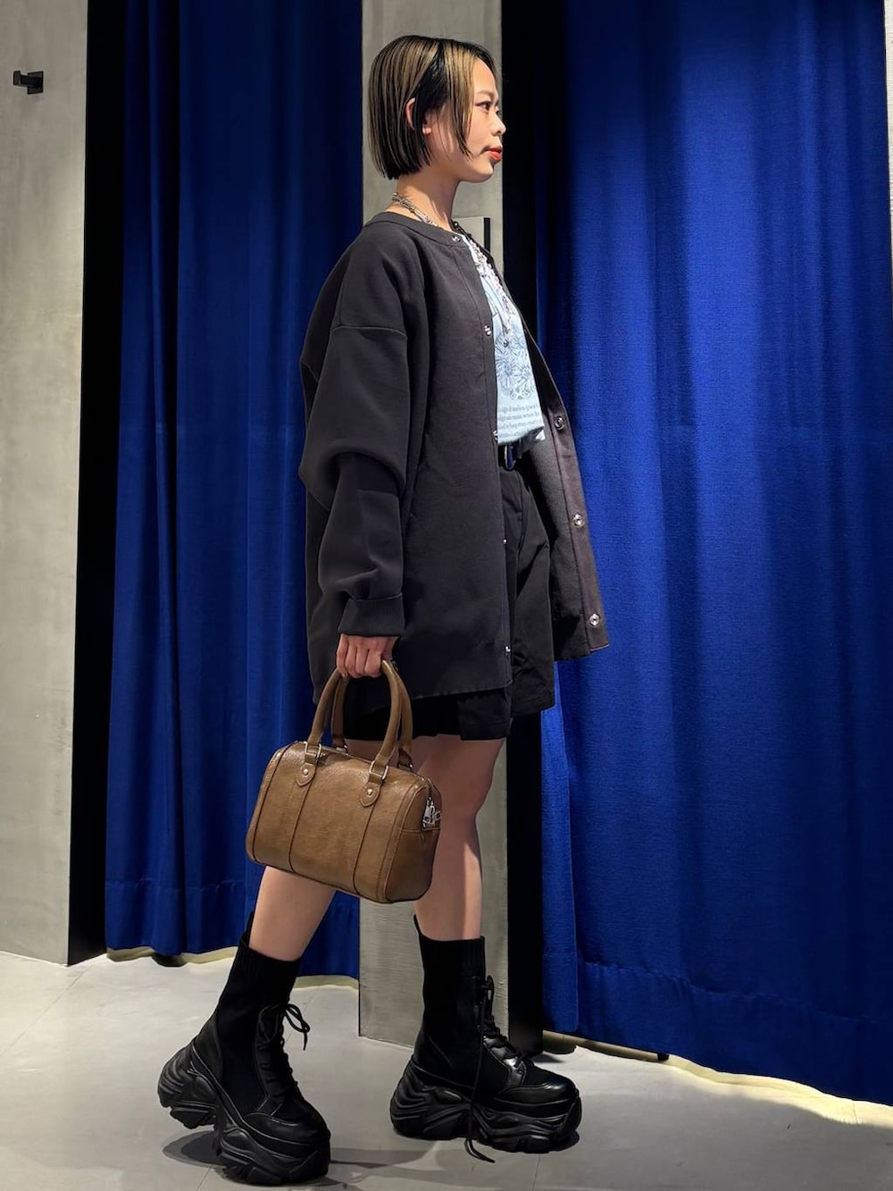 ブラック系のブーツ、ブラウン系のボストンバッグ、ブラック系のその他パンツを着用したレディースの春コーディネートの4枚目の写真