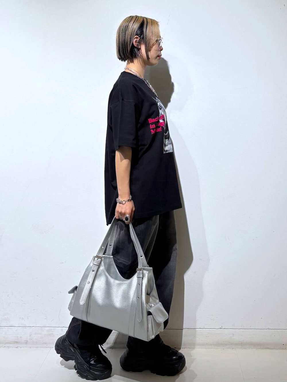 ブラック系のスニーカー、シルバー系のハンドバッグ、ブラック系のTシャツ/カットソーを着用したレディースの夏コーディネートの4枚目の写真